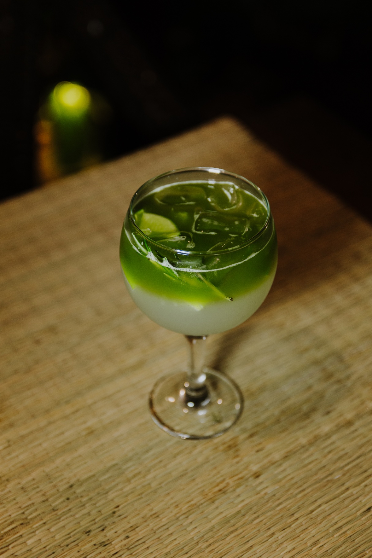 Drinque autoral verde servido no Oikos Bistro